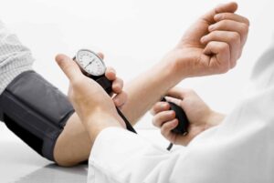 Profesional de la salud controlando la presión arterial de un adulto mayor